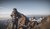 Zwei Wanderer beim Aufstieg auf felsigem Berggipfel im Sonnenlicht