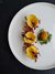Drei gefüllte Tortellini mit Schinken und Kräutern auf weißem Teller
