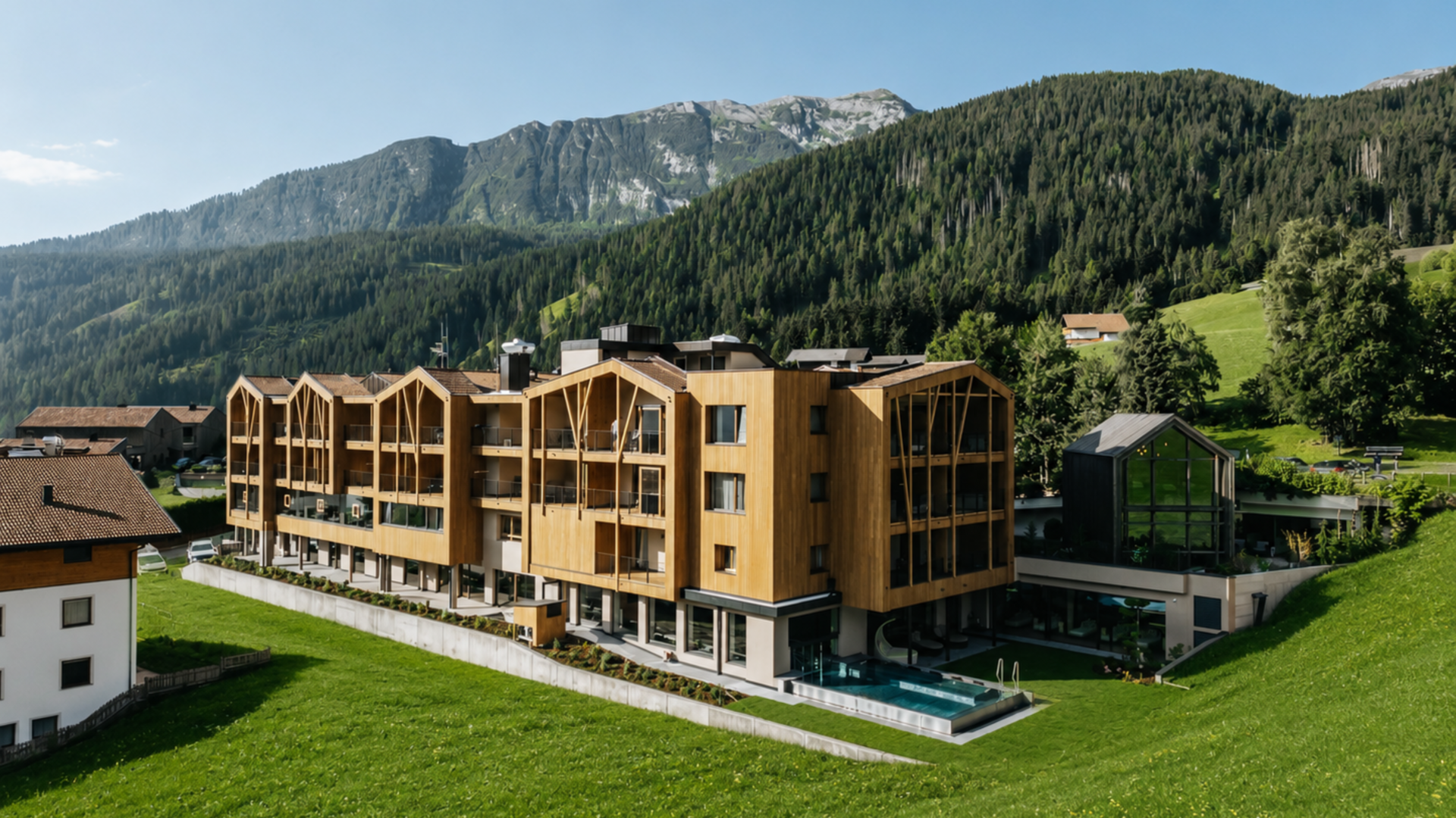 Neu bei uns im Gassenhof Modernes Hotelgebäude aus Holz in grüner Berglandschaft bei Sonnenschein