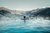 Person entspannt im beheizten Pool mit Blick auf schneebedeckte Berge