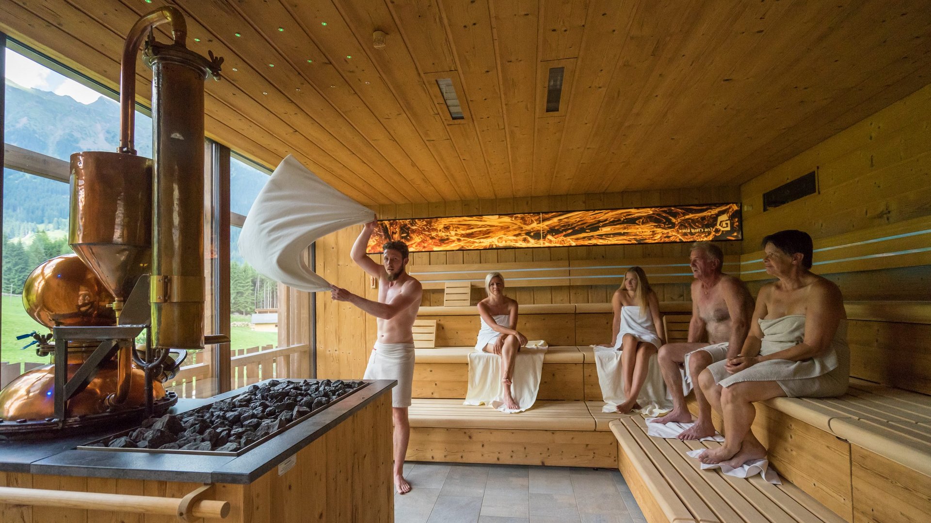 Our sauna realm Five people in a sauna, one waves a towel to spread steam