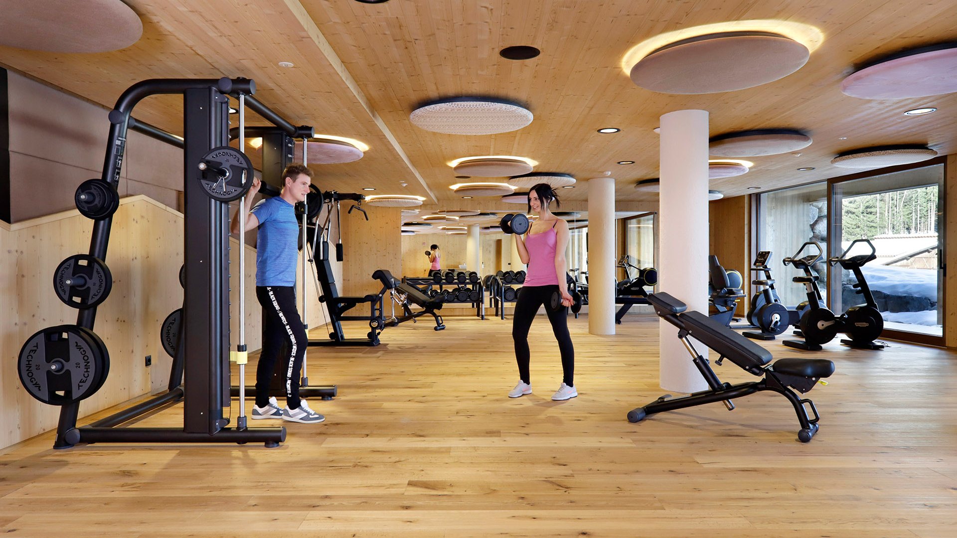 Fitness und Yoga Zwei Menschen trainieren mit Gewichten in modernem Fitnessraum mit Holzdecke