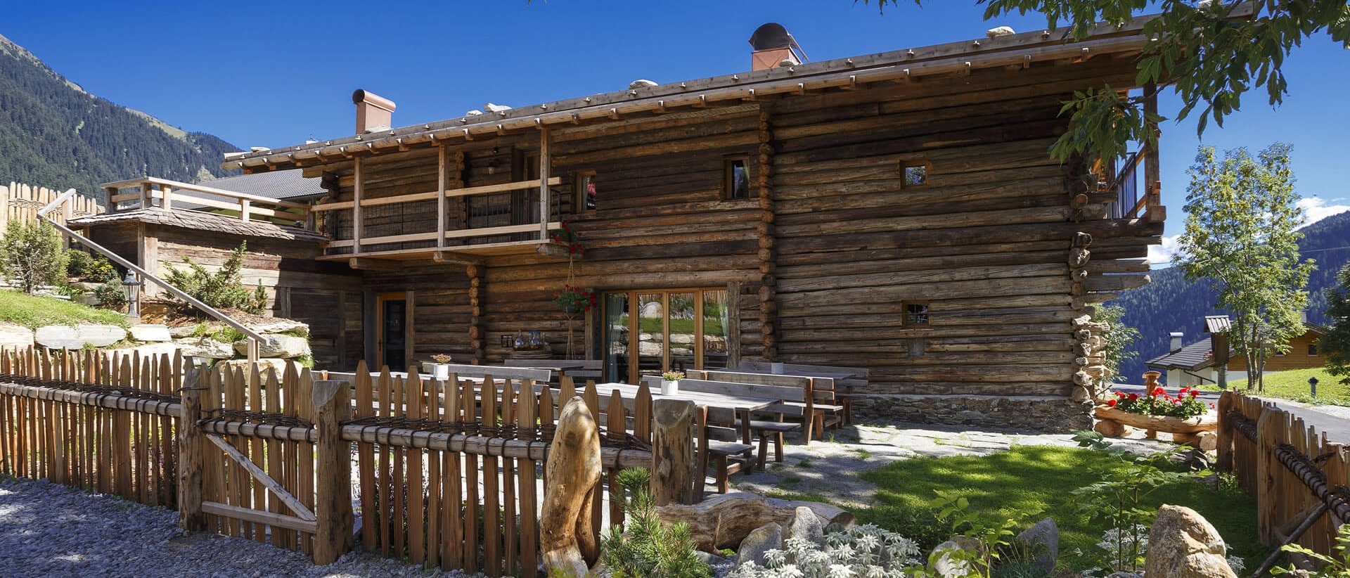 Urlaub anfragen Rustikales Holzhaus mit Garten und Bergblick bei klarem Himmel
