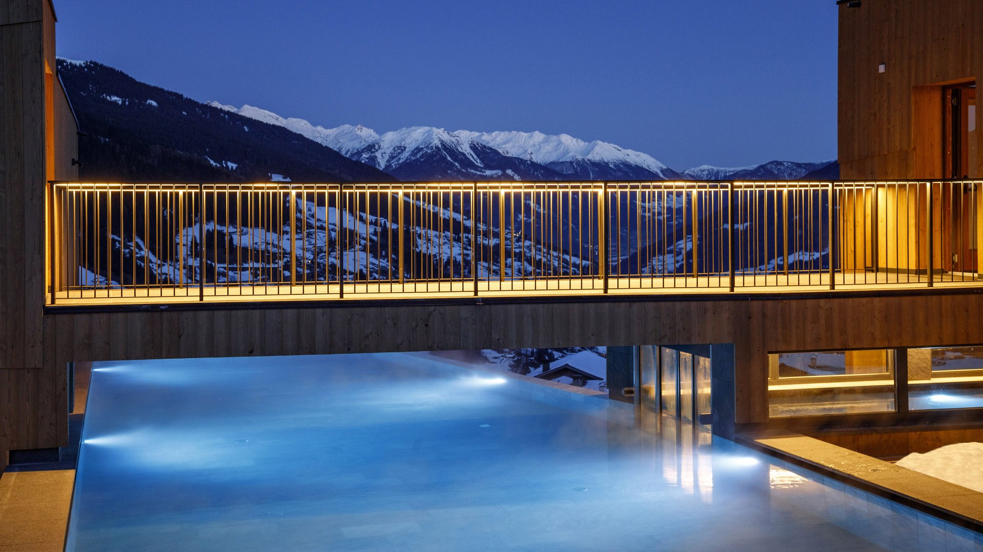 L’area wellness riservata agli adulti Piscina a sfioro illuminata con panorama montano innevato al crepuscolo