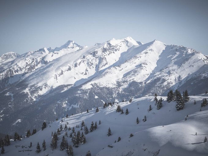 Winter hiking routes Snow-covered mountains with pine trees under clear blue sky
