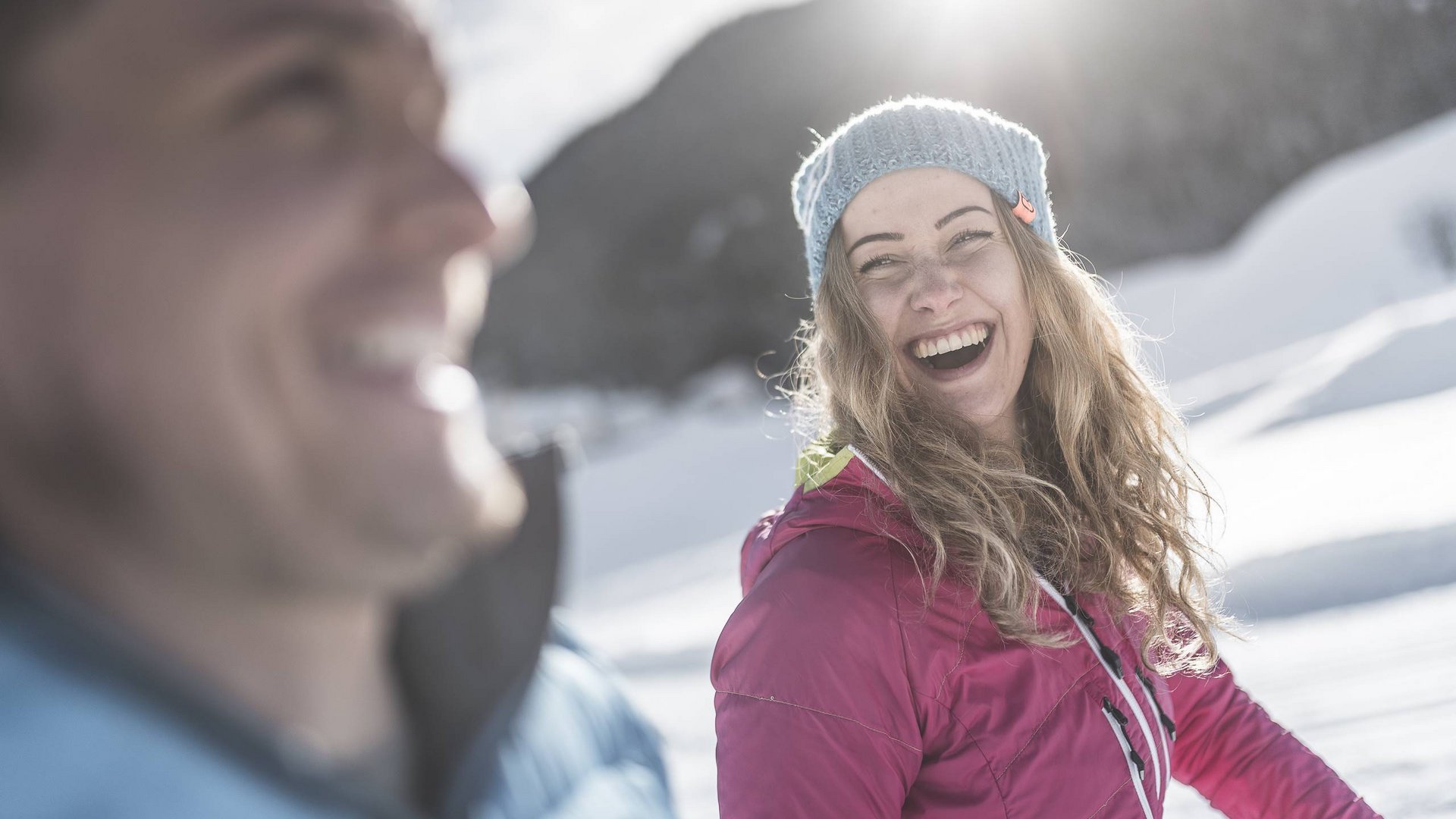 Winterwandern Lachende Frau in Winterkleidung bei sonnigem Schneetag