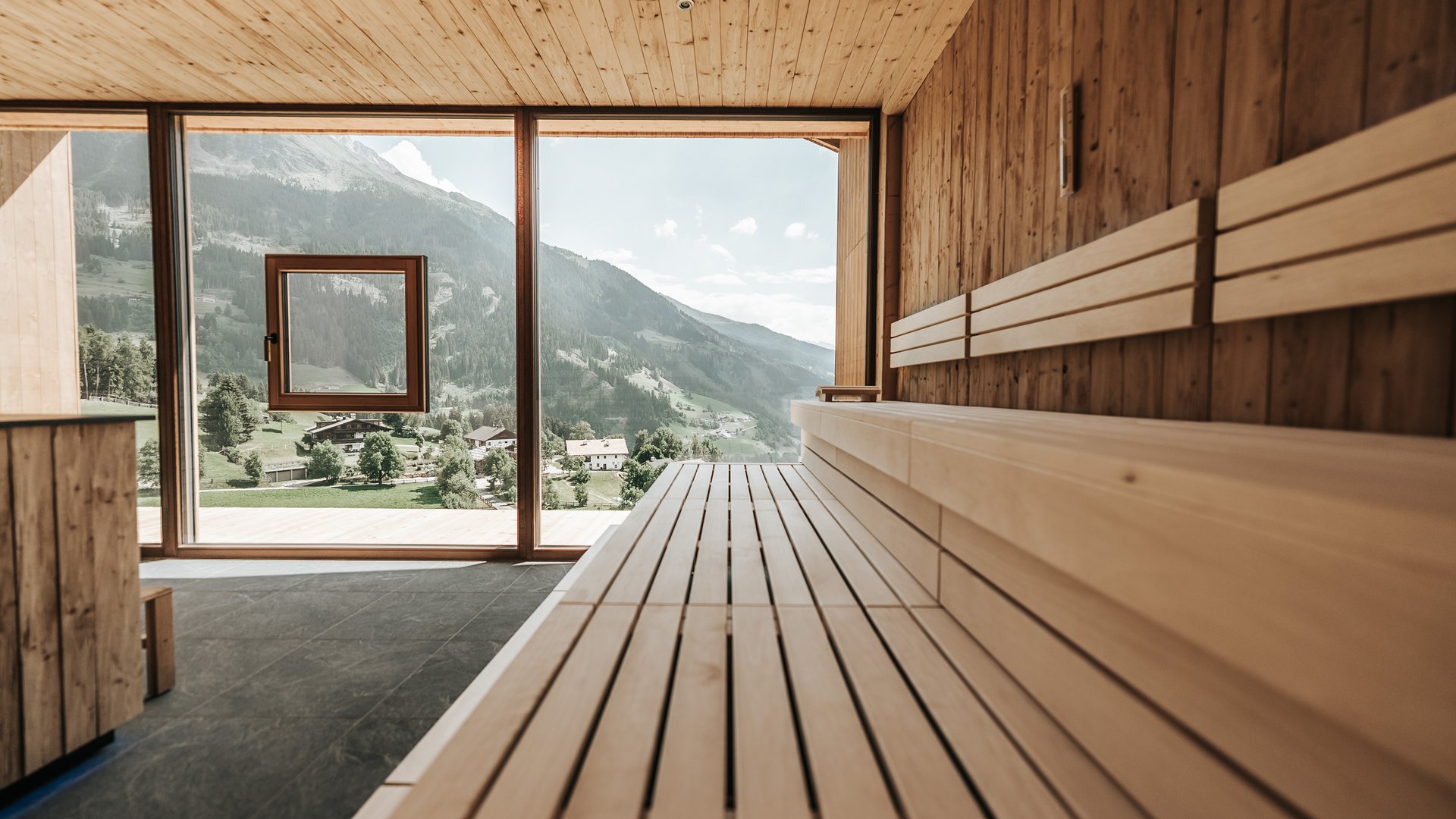 Logen Spa Sauna moderna con panche in legno e vista panoramica su montagne e vallata