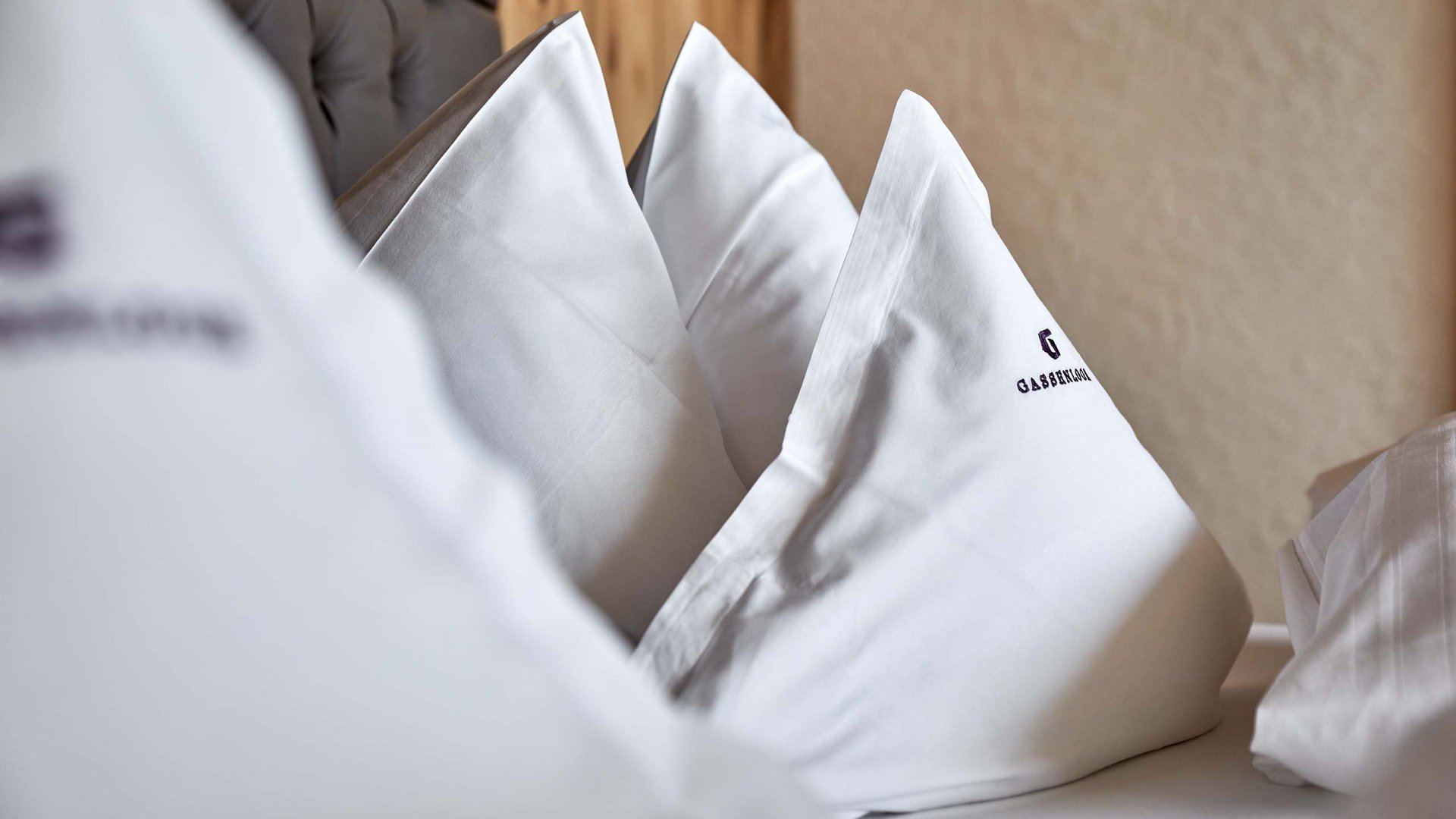 Inclusive services Three white pillows on a bed with a tufted headboard in the background.