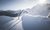 Zwei Menschen beim Schneeschuhwandern in verschneiter Berglandschaft bei Sonnenschein