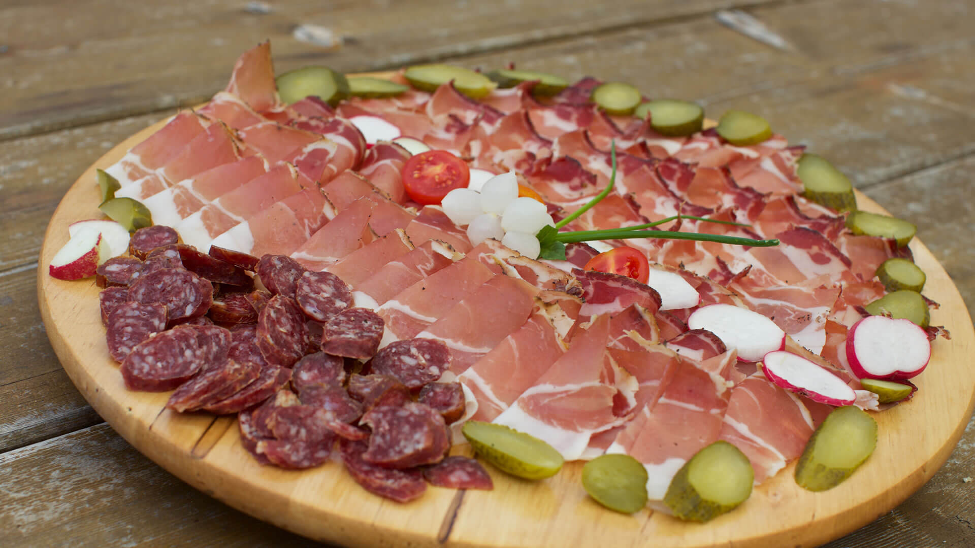 Urlaub in Ridnaun Verschiedene Wurstsorten und Gemüse auf Holzbrett angerichtet