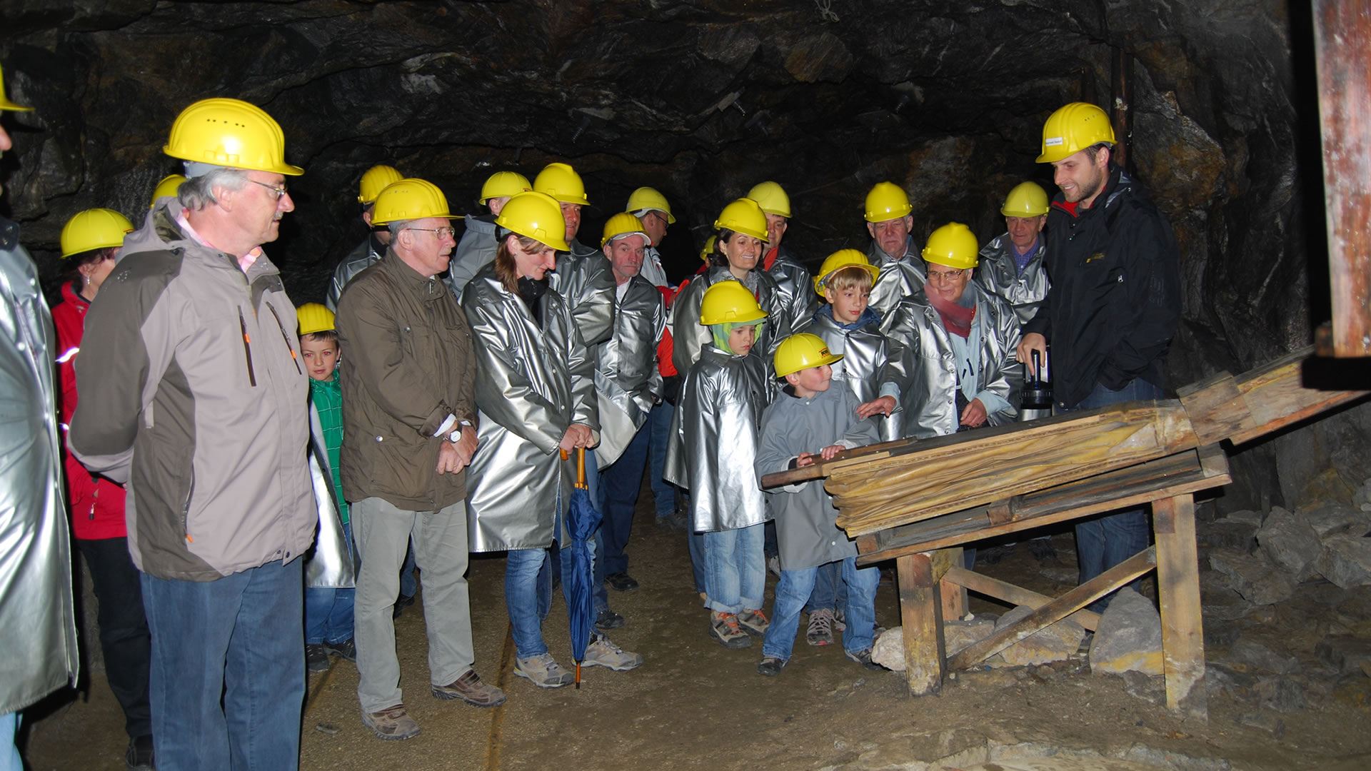 Summer experiences in South Tyrol Group of visitors wearing helmets and protective coats on a guided tour inside a mine